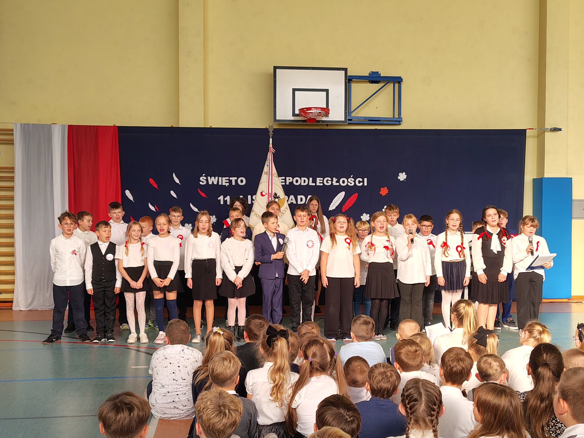 Uczniowie klas czwartych podczas wspólnego śpiewu piosenki "Wolność" podczas apelu z okazji Święta Niepodległości.