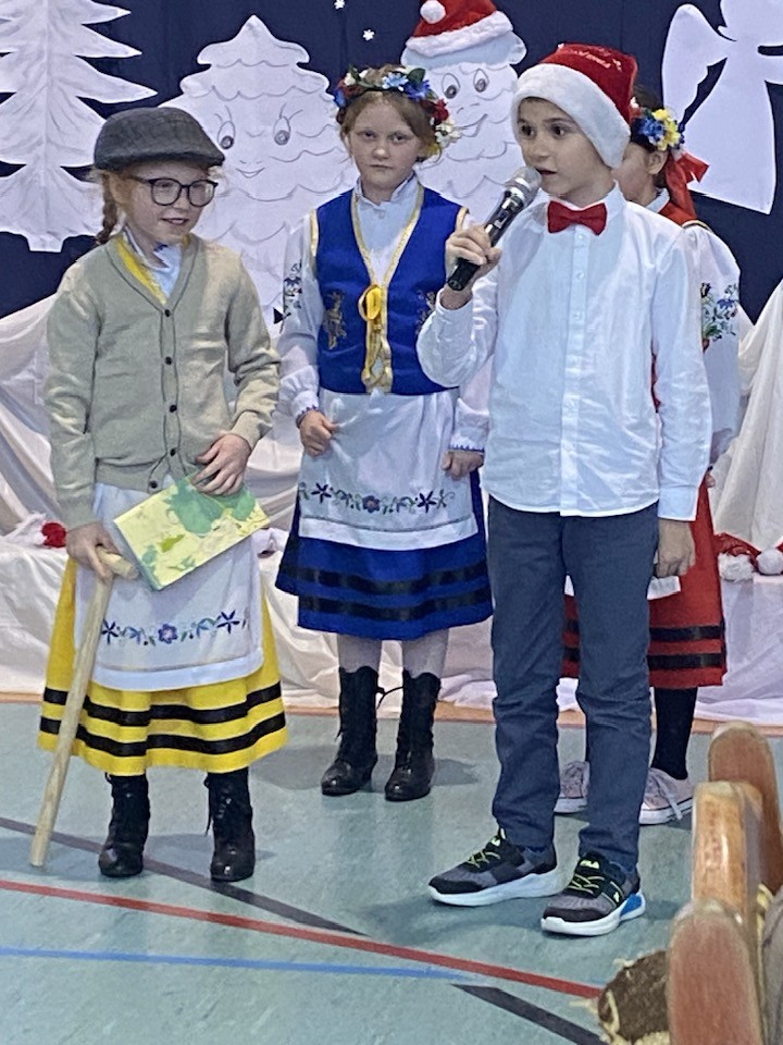 Uczniowie ubrani w stroje Kaszubskie recytują wiersz dla seniorów.