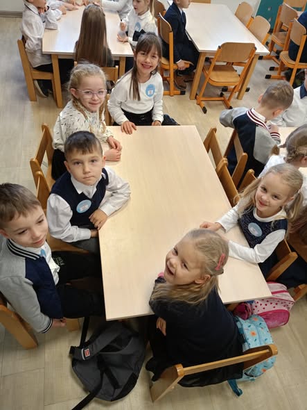 Uczniowie klasy zero siedzą przy stoliku w oczekiwaniu na konkurs.