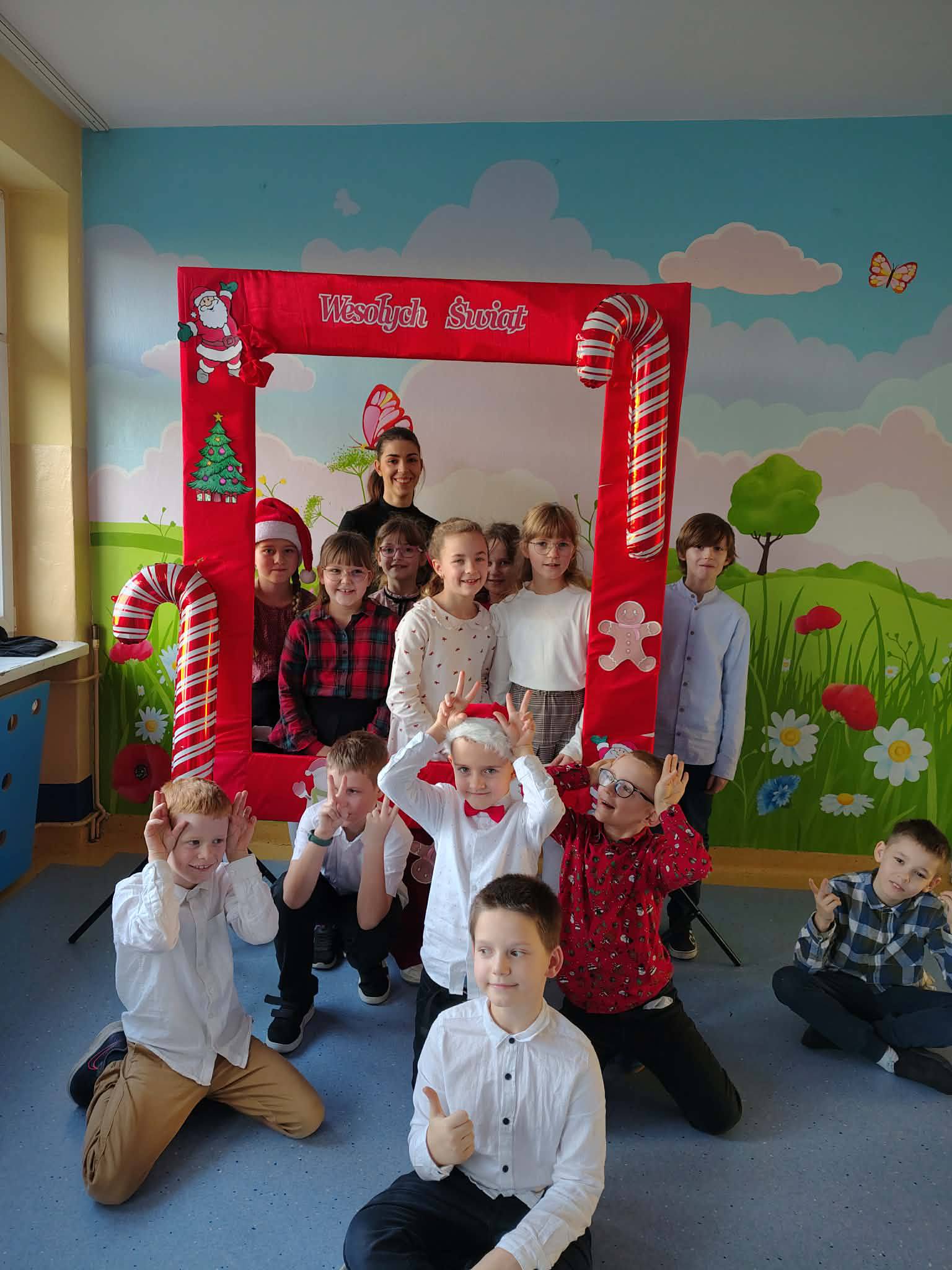 Uczniowie klasy 2b z wychowawczynią na tle ścianki świątecznej.