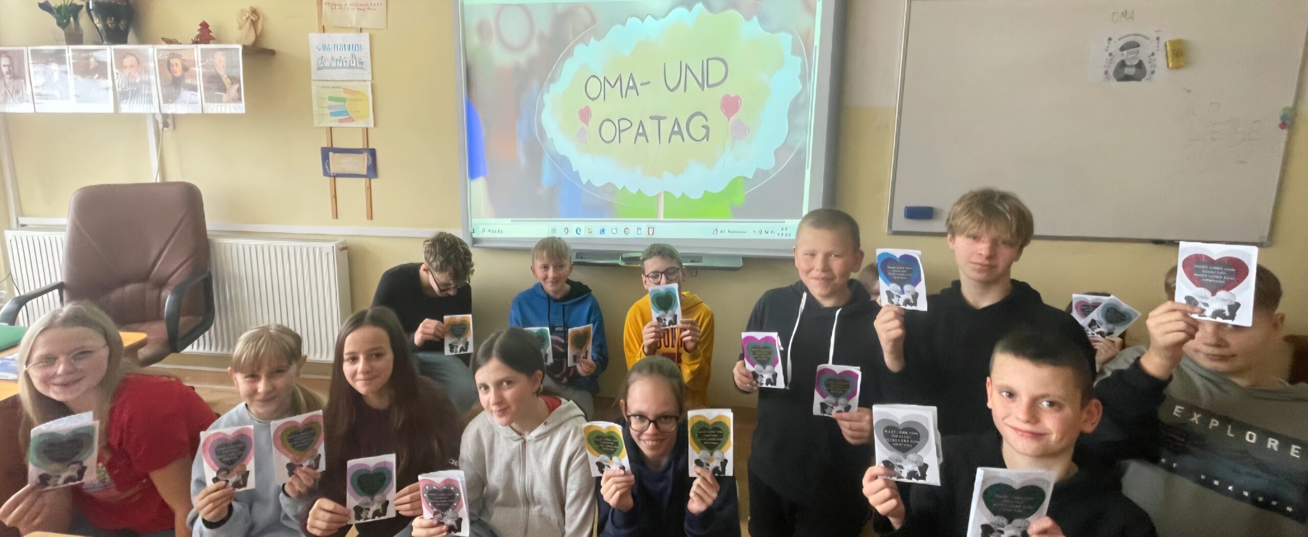 Uczniowie klasy VIb pozują do wspólnego zdjęcia trzymając kartki z życzeniami w języku niemieckim dla swoich dziadków.