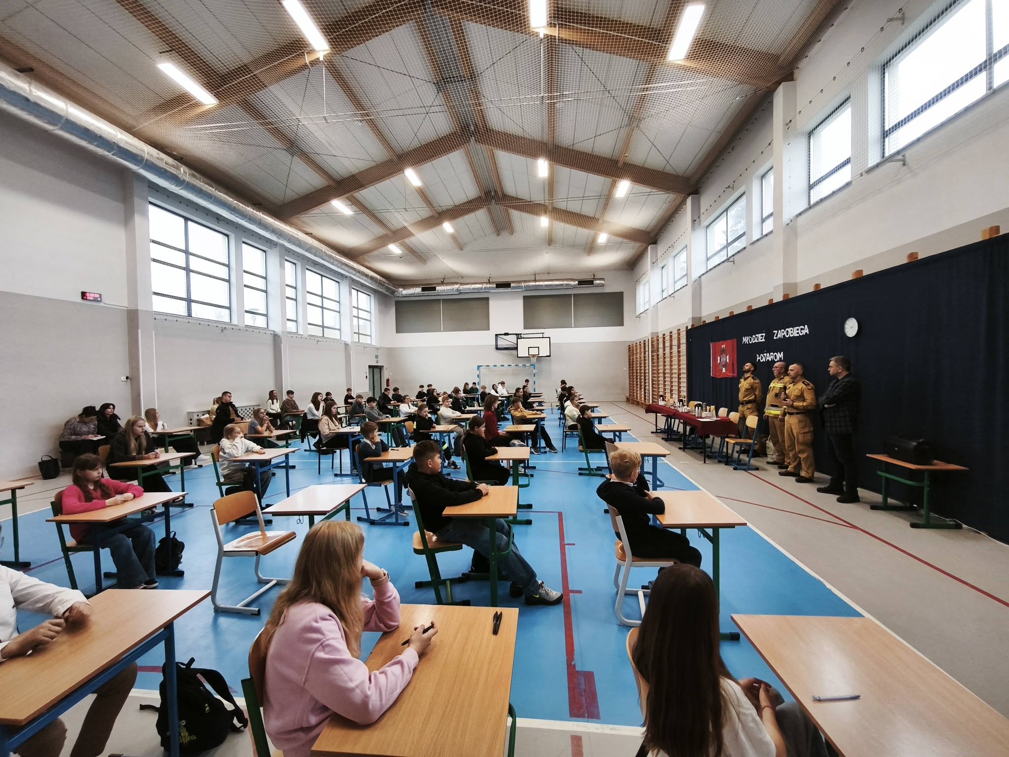 Uczniowie siedzą prze stolikach podczas konkursu.