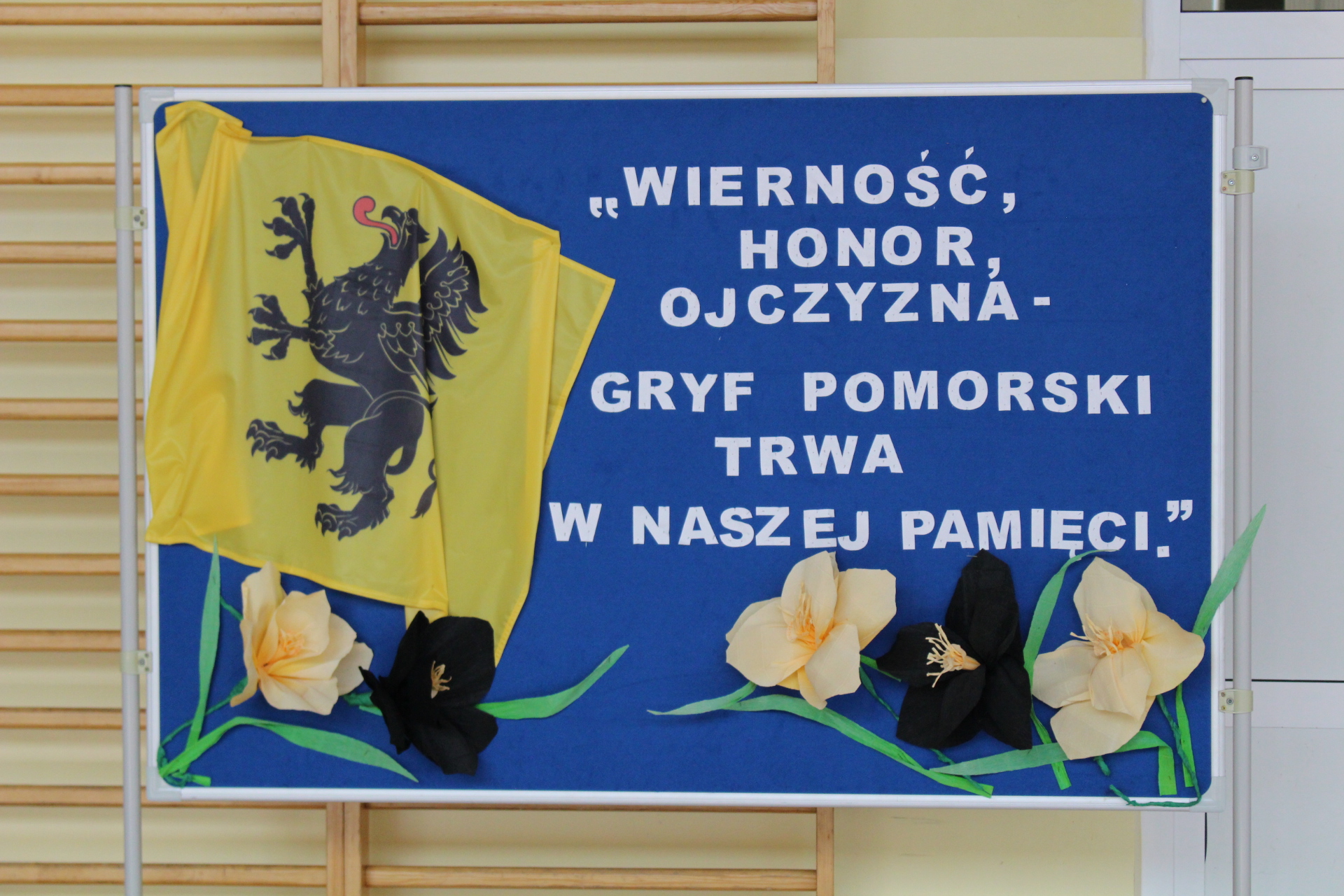 Zdjęcie nr 1 Przedstawia gazetkę szkolną, na której znajduje się flaga Gryfa Pomorskiego wraz z hasłem: ,,Wierność, honor, ojczyzna - Gryf Pomorski trwa w naszej pamięci. " 