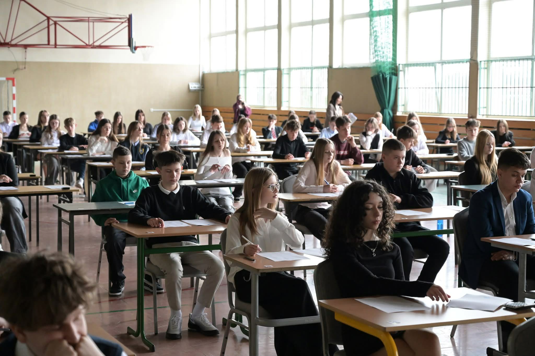 Uczniowie siedzą w ławkach podczas pisania testu na konkursie.