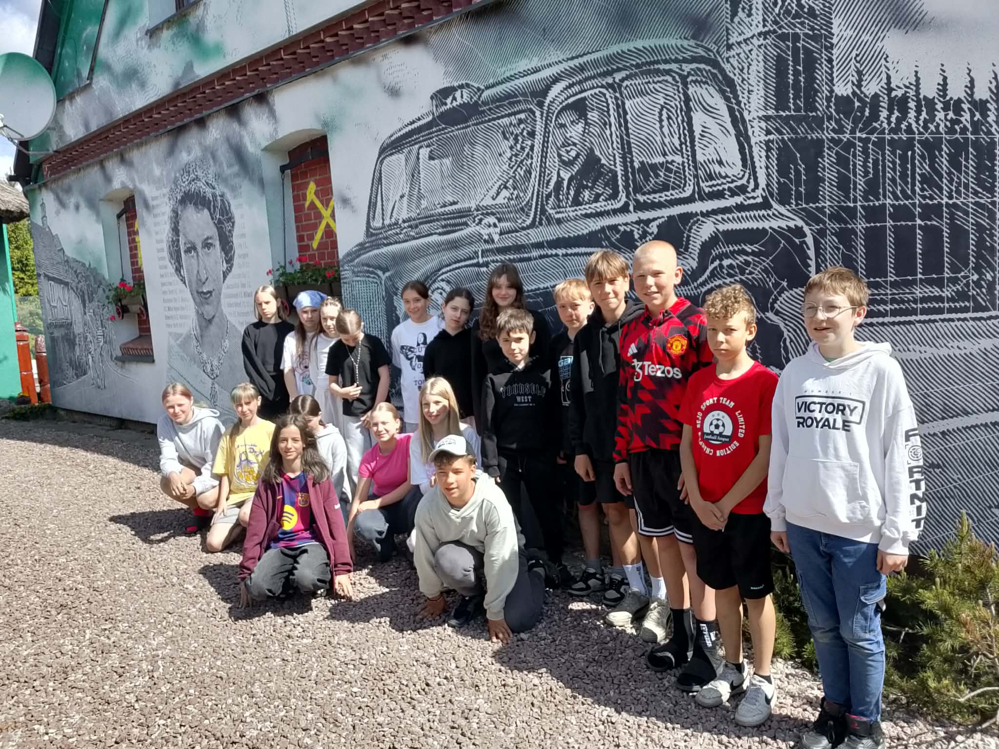 Zdjęcie grupowe uczniów klasy 5 i 6 biorących udział w Zielonej Szkole w tle mural.