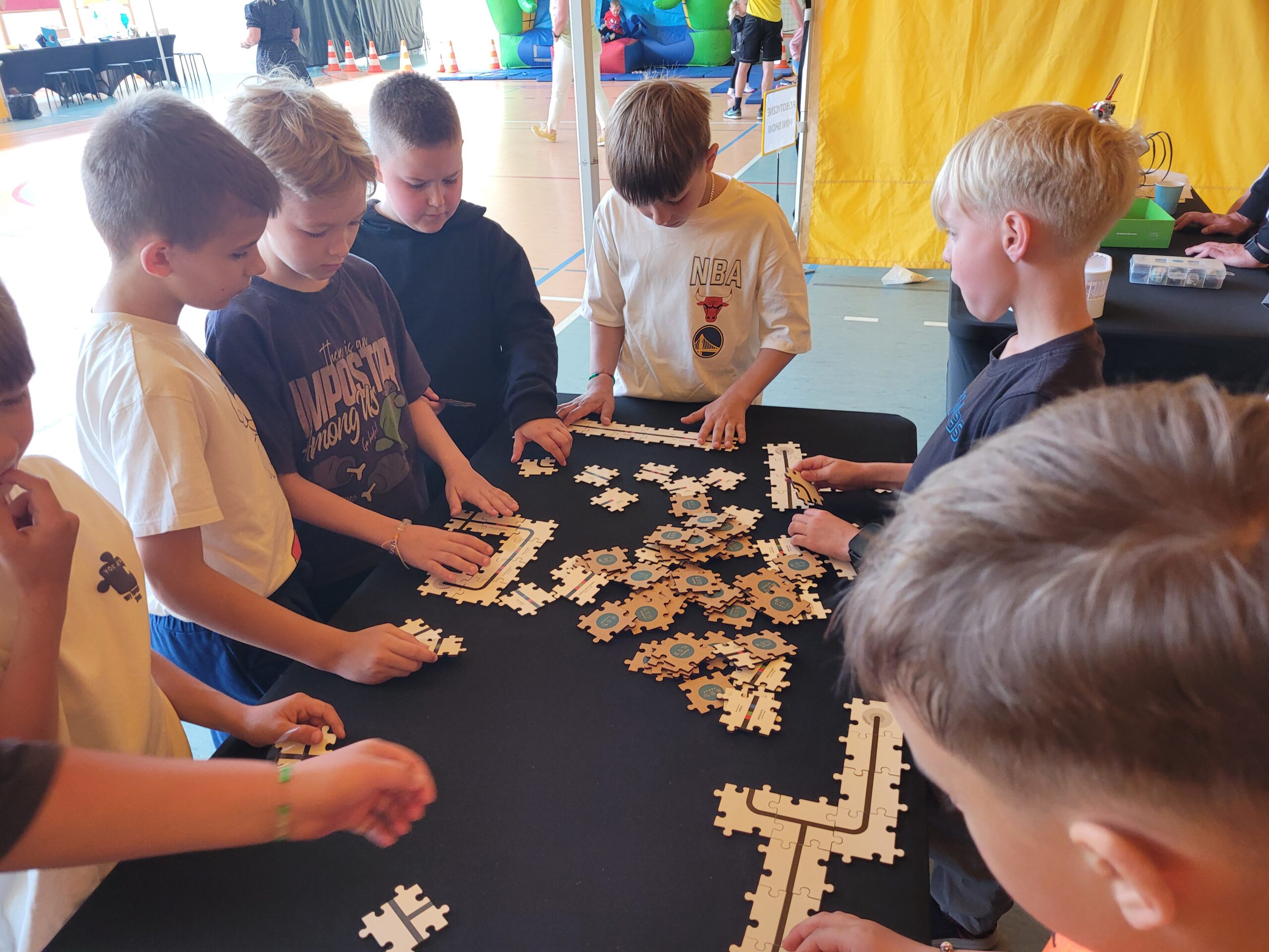 Uczniowie składają układankę z puzzli.