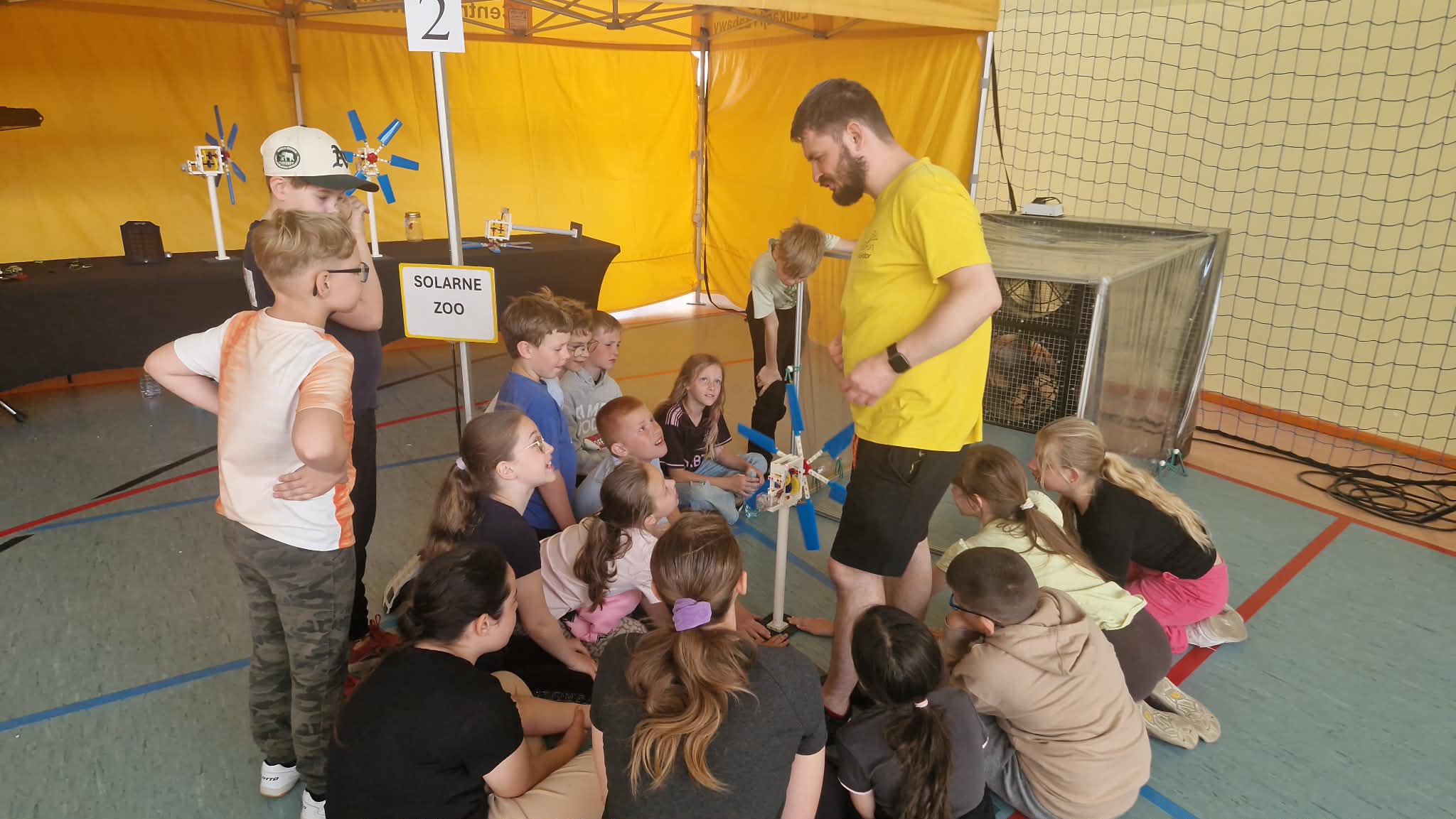 Uczniowie na stanowisku solarne zoo patrzą jak wiatr porusza wiatrakiem.