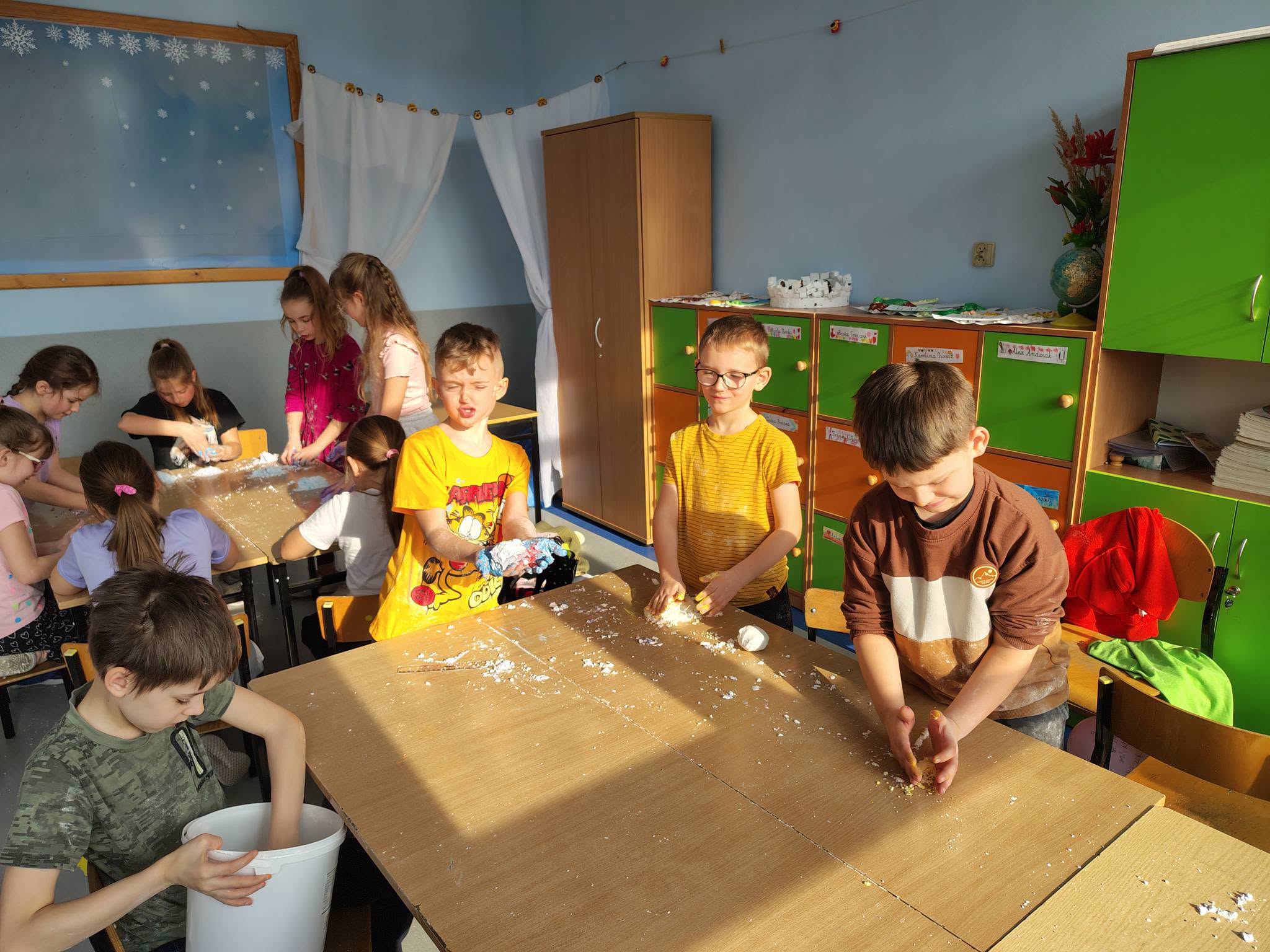 Uczniowie klasy IIb uczestniczą w zajęciach sensorycznych, wykonując kolorową masę sensoryczną.