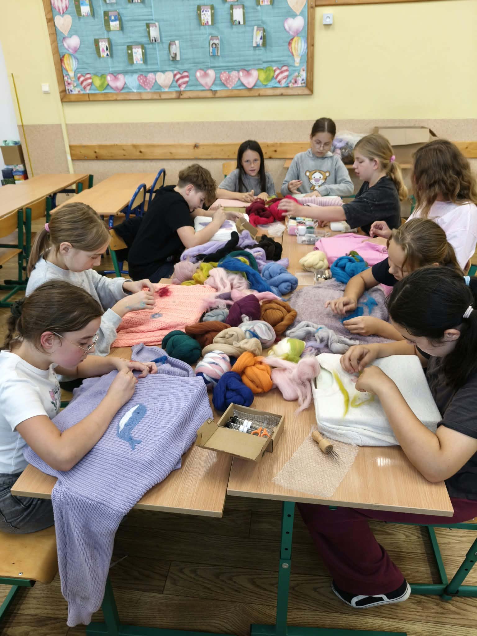 Kolejna grupa uczniów klas 4–5 filcuje przy wspólnym stole podczas zajęć Małej Pracowni Krawieckiej.