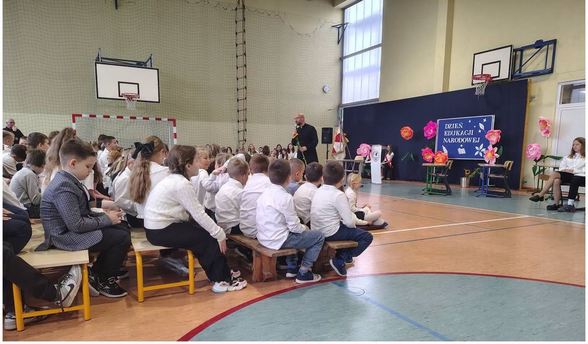 Ksiądz proboszcz rozmawia z uczniami podczas apelu.